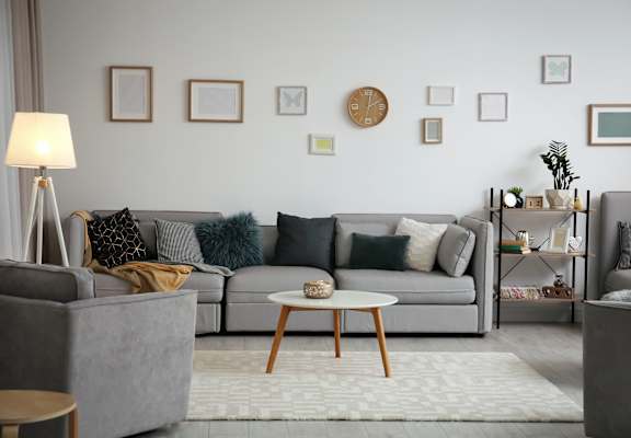 A living room with a grey couch, a wooden coffee table, and a lamp.