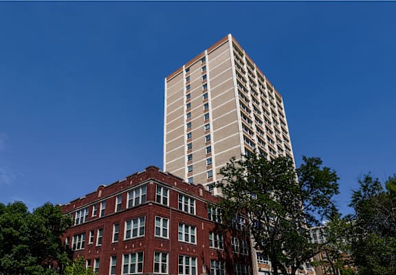 A red brick building with a tall white building behind it.