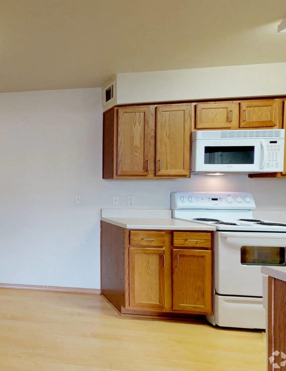 an empty kitchen with white appliances and wooden cabinets