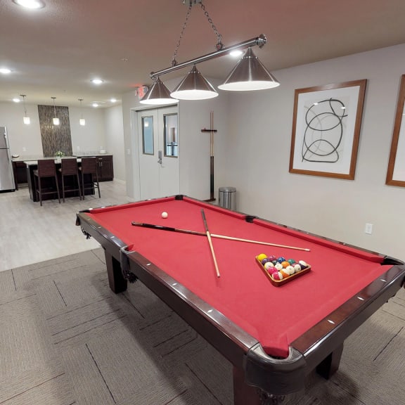 a red pool table in a room with a bar and a dining room
