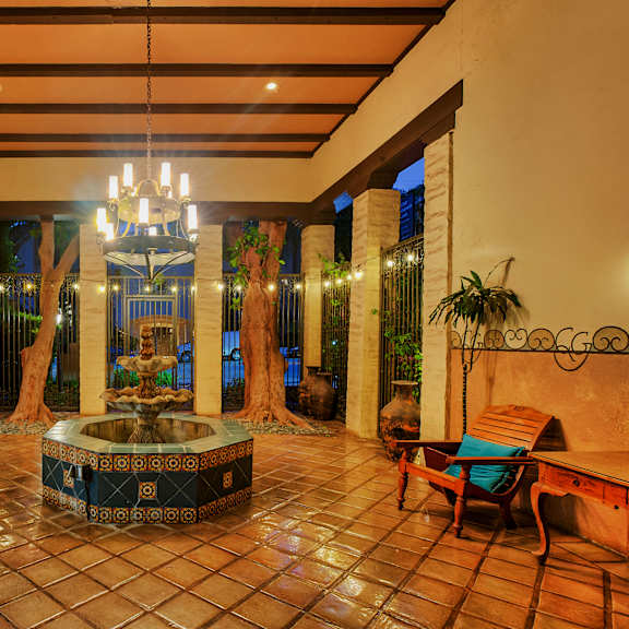 A large atrium with a fountain in the middle and a bench on the left.