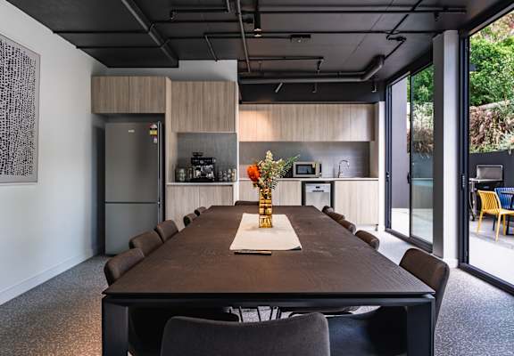 a conference room with a table and chairs and a kitchen