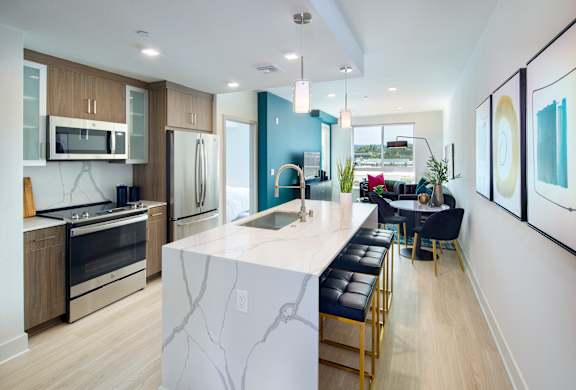 A modern kitchen with a marble island and bar stools.