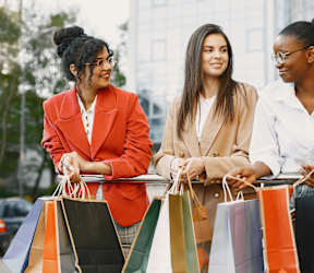 Three women with shopping bags in the city.