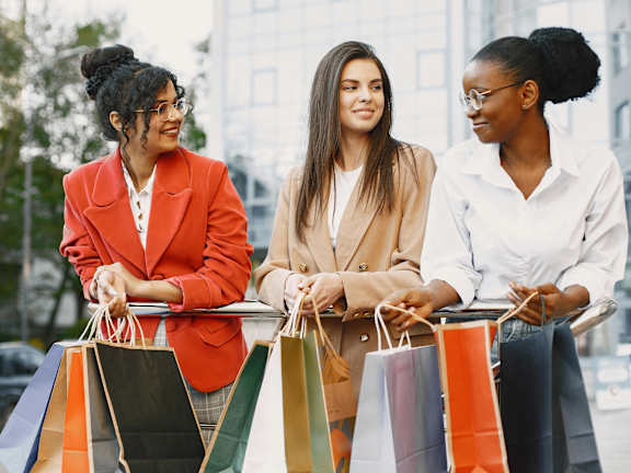 Three women with shopping bags in the city.