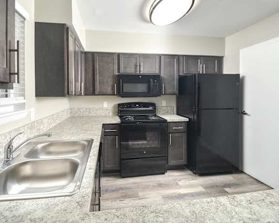 a kitchen with black appliances and a stainless steel sink