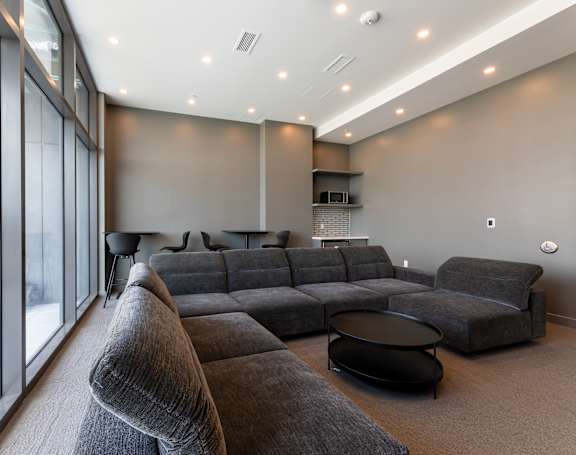 A grey sectional sofa with a black coffee table in front of it.