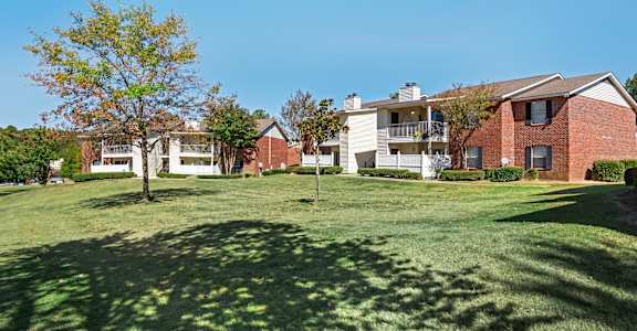 A large grassy field in front of apartment buildings.