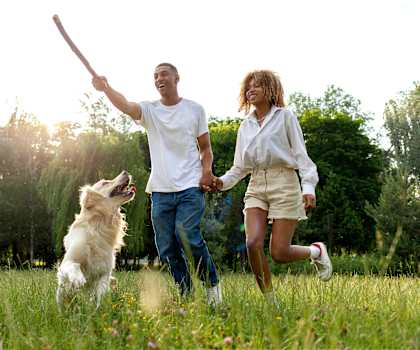 a man and woman playing with a dog in a field  at South Winds Apartments, Fall River
