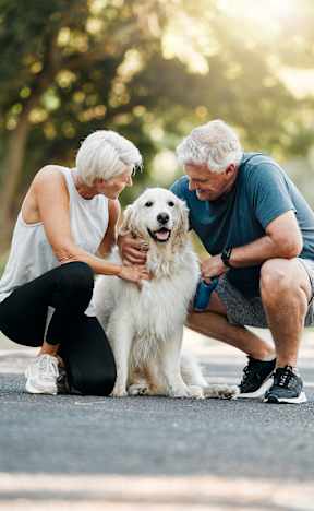 An older couple petting a white dog on a road.at Prairie Encore, Dardenne Prairie Missouri