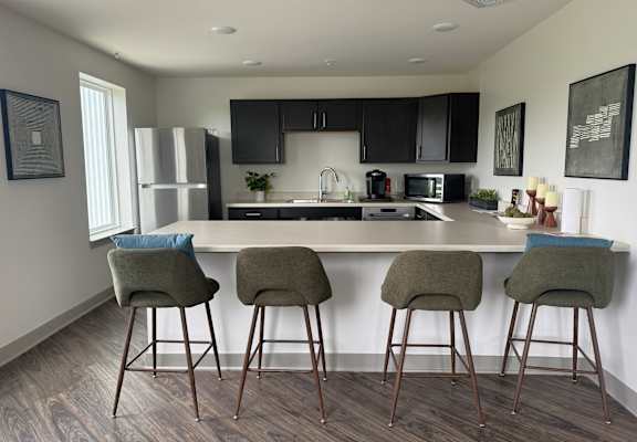 A kitchen with a bar area and three bar stools.