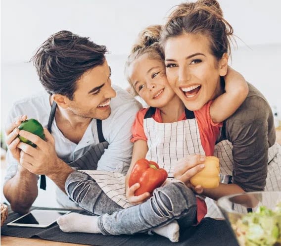a man and woman sitting at a table holding a child and looking at a tablet