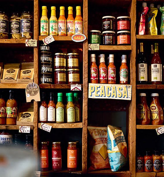 a shelf filled with different bottles of hot sauce and other drinks