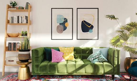 a living room with green couch and paintings on the wall