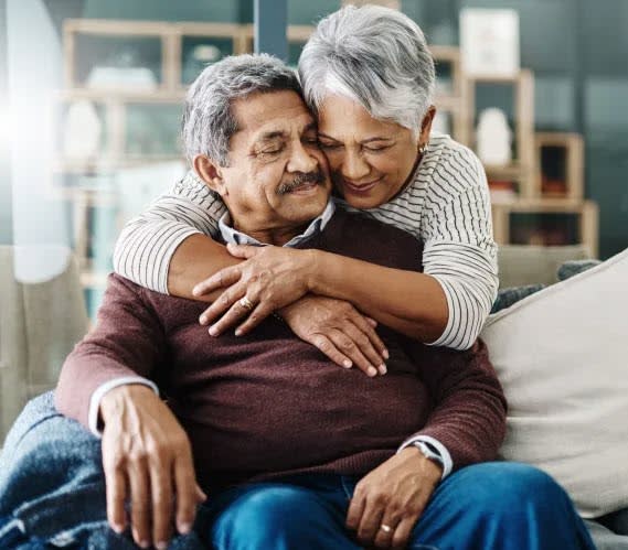 an older couple sitting on a couch with their arms around each other