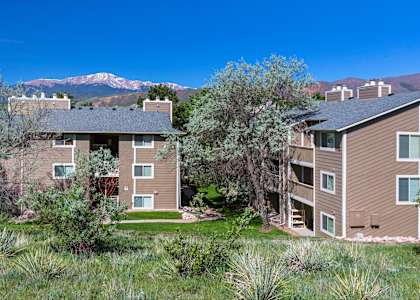 Apartment buildings with greenery in front and mountains in the background.