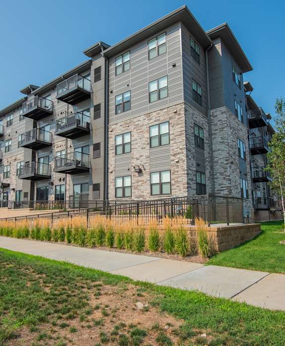 A modern apartment building with balconies and a green lawn in front.