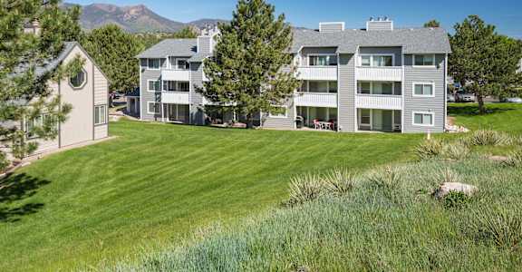 A large grey building with a green lawn in front.