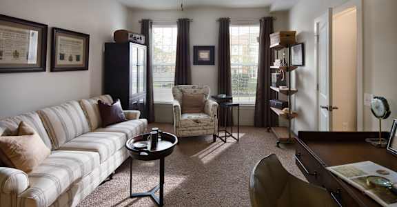 a living room with a couch and a chair and a desk