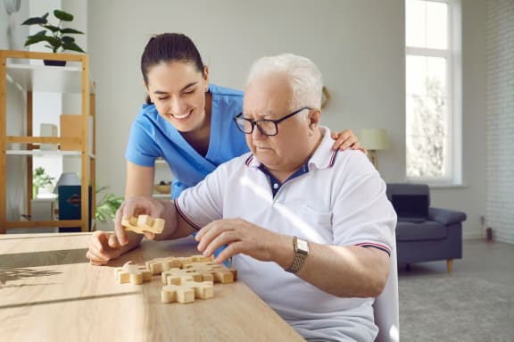 An older man and a young woman playing with wooden puzzle blocks