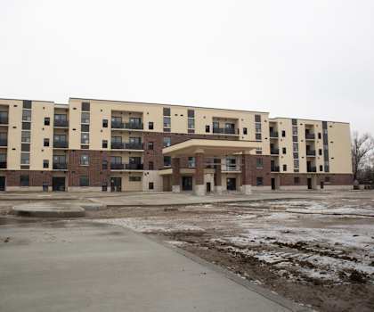 A large, modern apartment building with a parking lot in front.