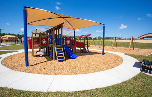 A playground with a blue and yellow canopy and a slide.