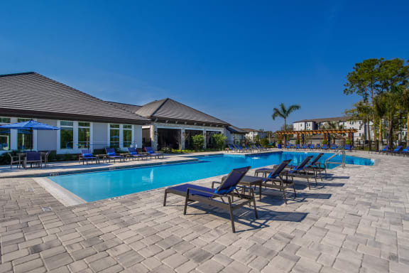 a resort style pool with lounge chairs and umbrellas