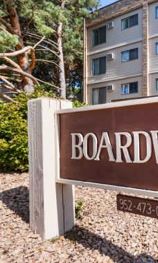 A brown sign that says Boardwalk in front of a building.