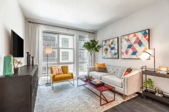 A living room with a grey couch, a yellow chair, a red coffee table, and a painting on the wall. at Coda at Bryant Street, Washington, DC 20002