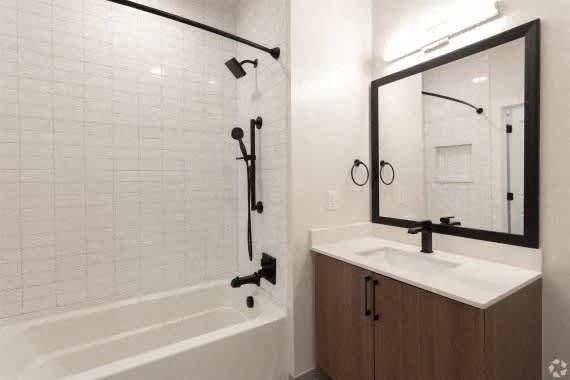 A bathroom with a white tub, sink, and mirror. at Coda at Bryant Street, Washington, DC 20002
