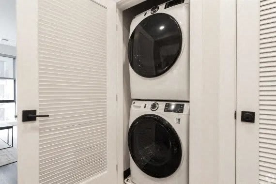 A white washing machine is in a cabinet with a black door. at Coda at Bryant Street, Washington, DC 20002