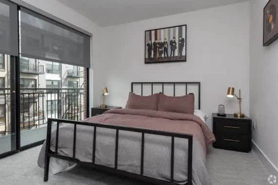 A bedroom with a large bed, a nightstand, and a painting on the wall. at Coda at Bryant Street, Washington, DC 20002