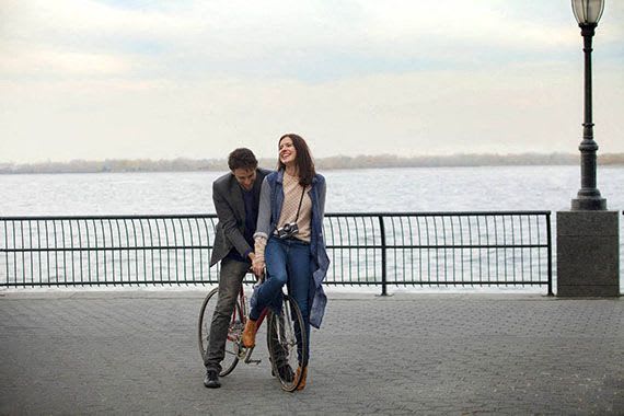A man and a woman are walking together on a sidewalk near a body of water.