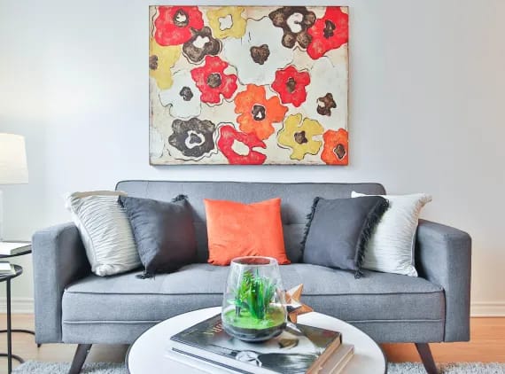 a living room with a grey couch and a painting on the wall