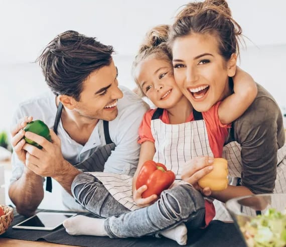 a man and woman sitting at a table holding a child and a tablet