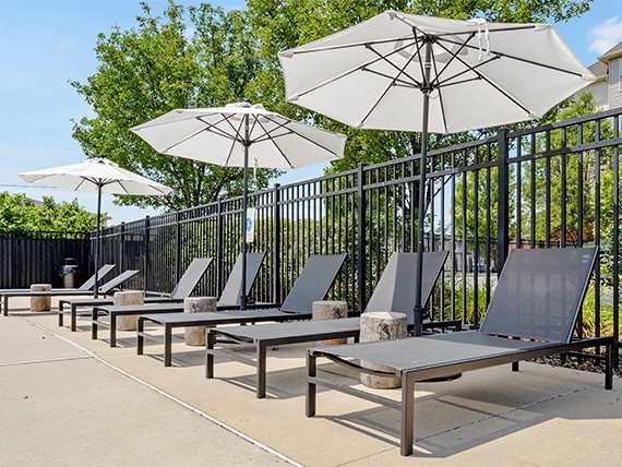 A row of black metal chairs are lined up under white umbrellas  at Bristol Station Apartments, Carteret, New Jersey