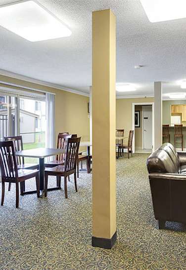 A large room with a long column in the middle and a dining table with chairs. at Lou Park, St. Louis Park, MN, 55426