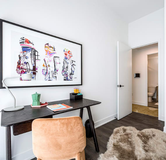 a home office with a desk and a painting on the wall