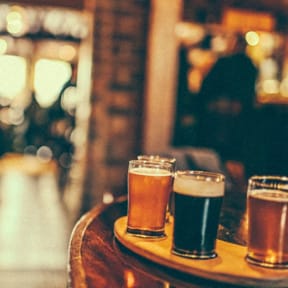 three beers sitting on a wooden table in a bar