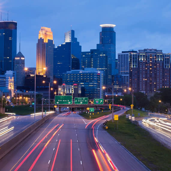 A cityscape at dusk with a highway leading into the city.