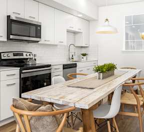A modern kitchen with a wooden table and white chairs.