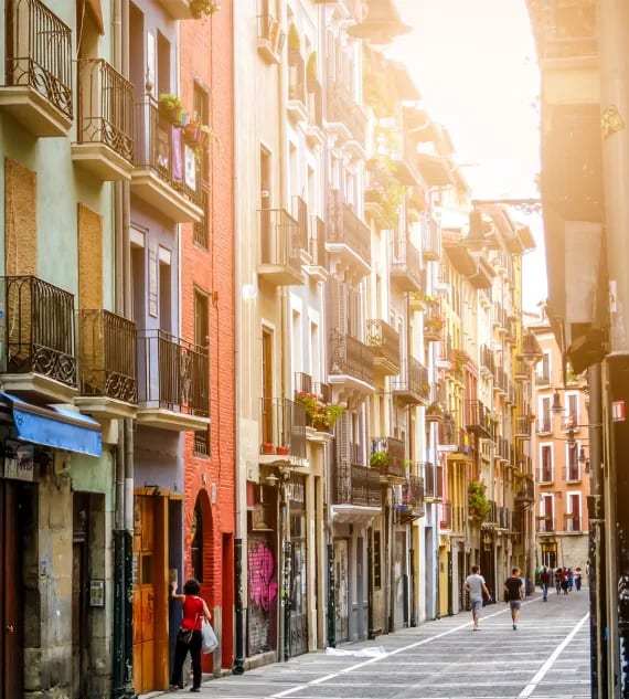 a street with people walking down it in the sun