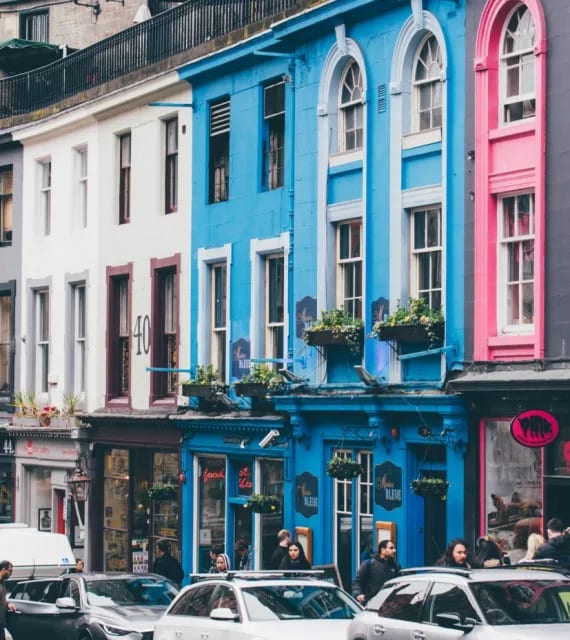 a city street with cars parked in front of colorful buildings