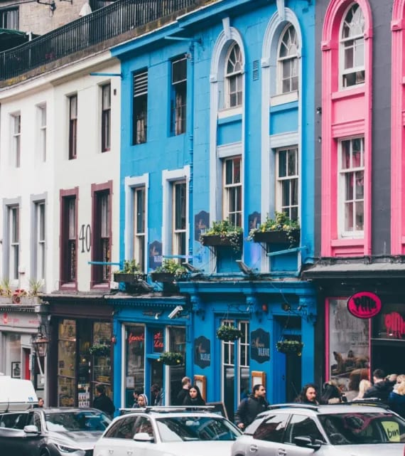 a city street with cars parked in front of colorful buildings