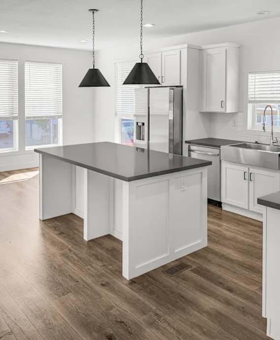 A kitchen with a black island in the middle of white cabinets.