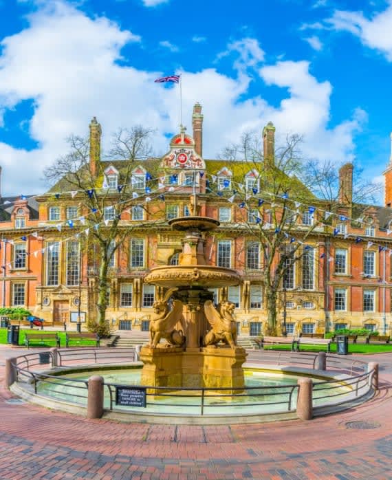 a fountain in front of a building with a flag