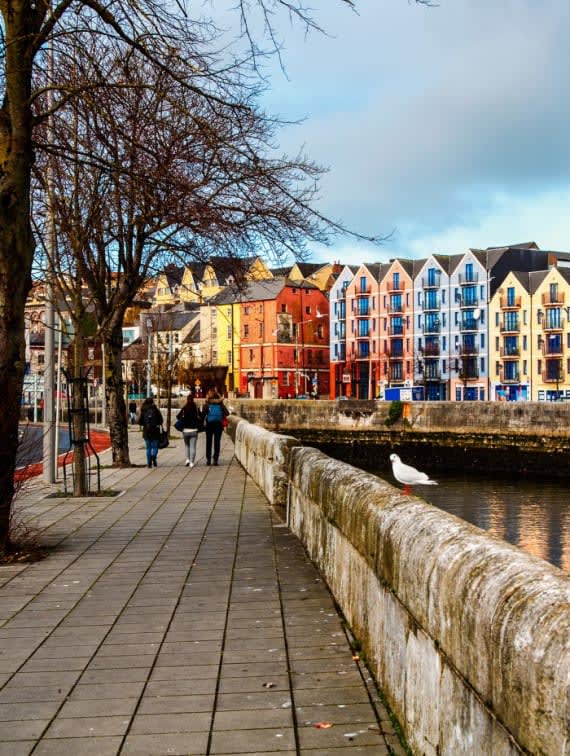 people walking along a canal in front of colorful buildings