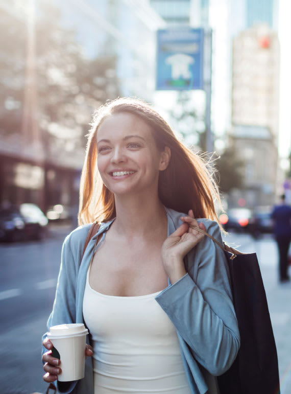 a woman walking down the street with a cup of coffee