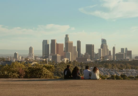 a group of people sitting on a hill with the los angeles skyline in the background