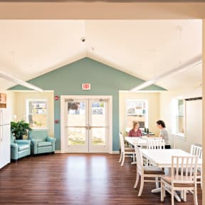 a woman sitting at a table in an open kitchen and dining room